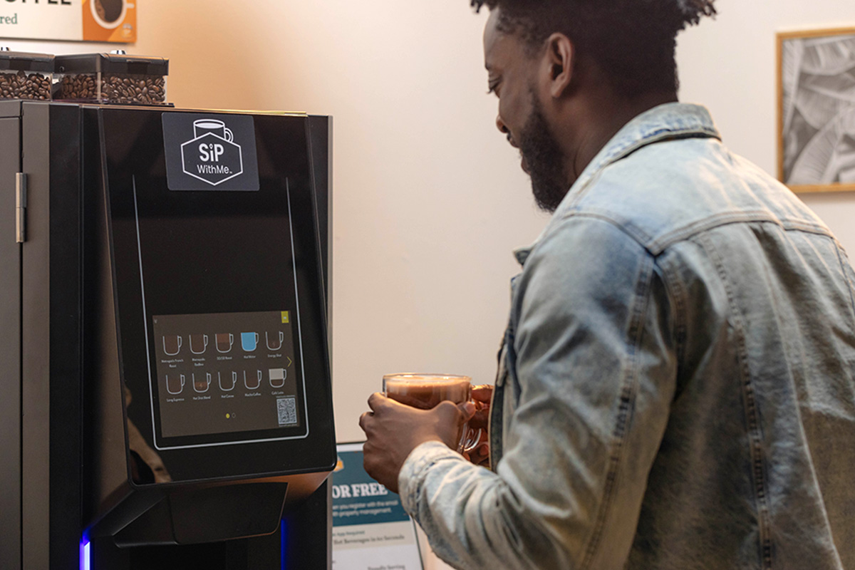 male picks up a mug from a sipwithme coffee amenity