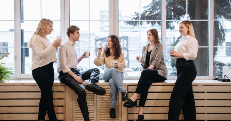 A group of young professionals enjoying coffee together in a bright, modern communal space, fostering connection and engagement—illustrating the power of coffee in building a sense of community.