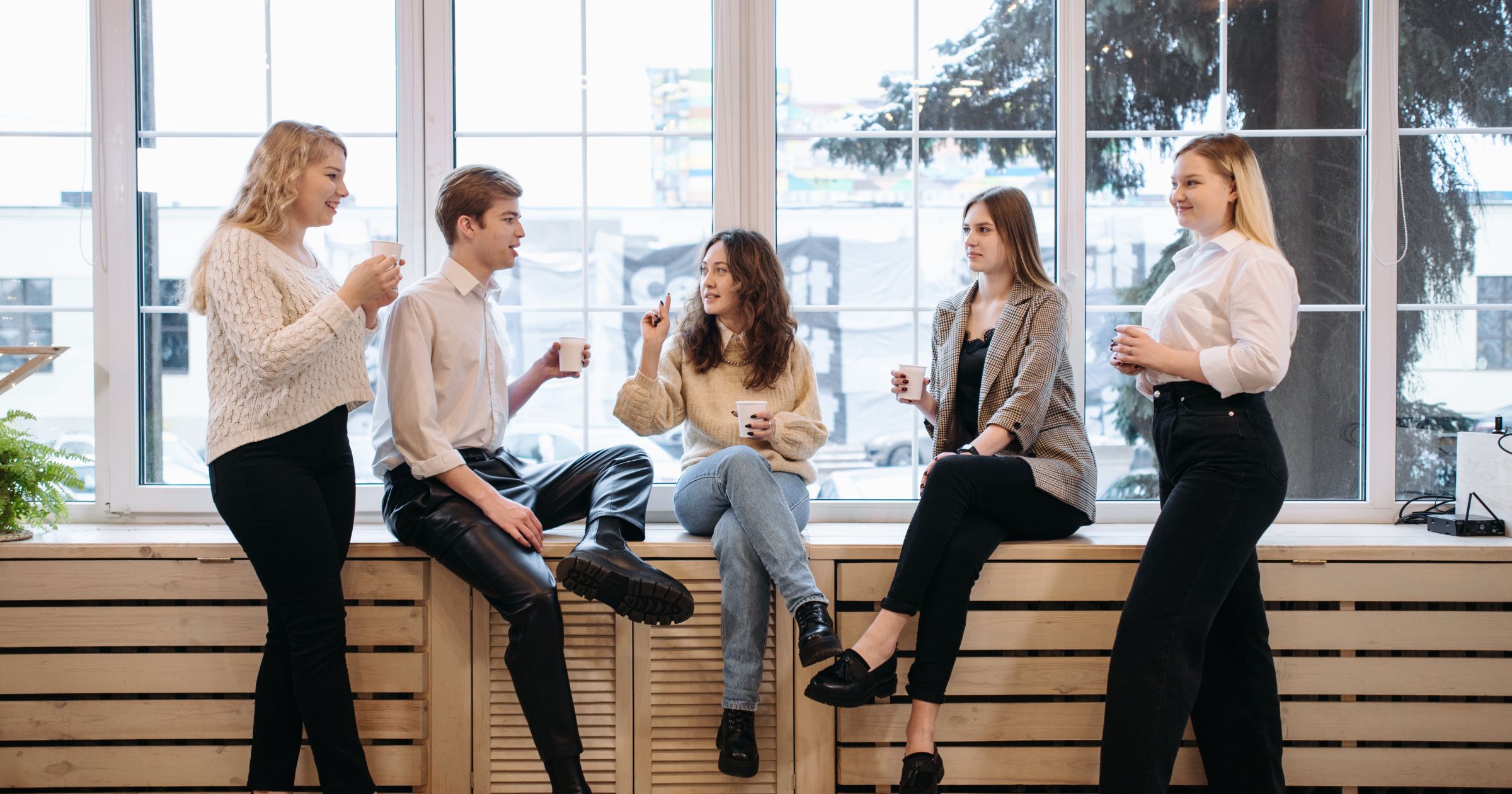 A group of young professionals enjoying coffee together in a bright, modern communal space, fostering connection and engagement—illustrating the power of coffee in building a sense of community.