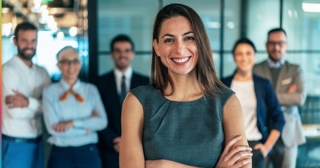 Confident business leader standing with team in modern office representing leadership in the era of AI