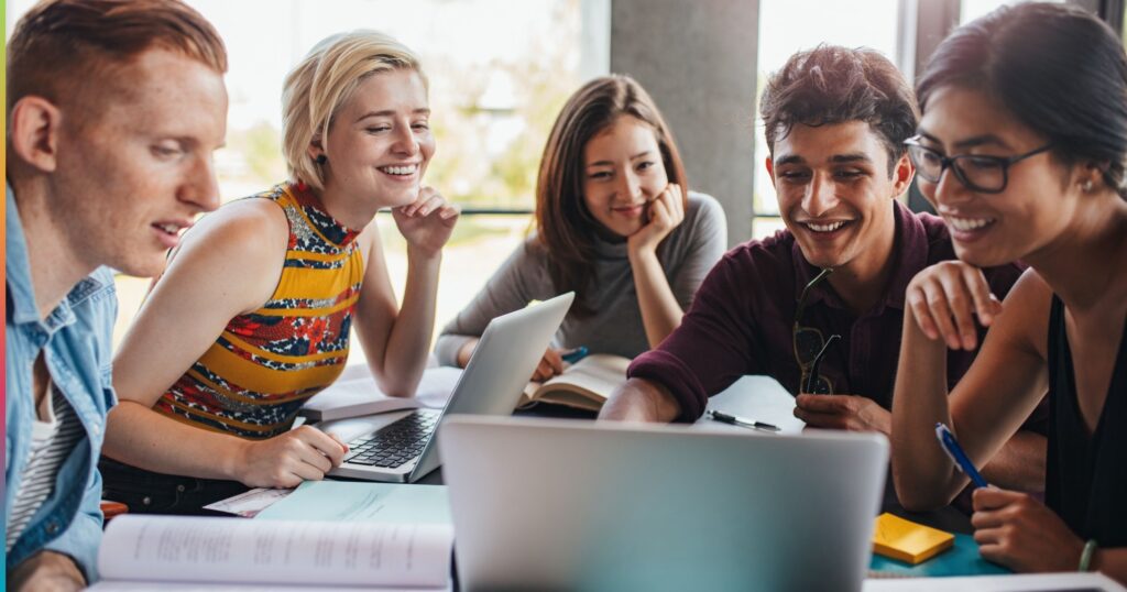 Students working together with laptops and study materials in a shared student housing amenity space, representing modern living and collaborative environments