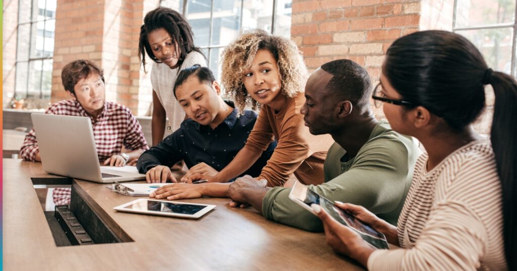 Students working together around a table with laptop and tablet in a shared student housing workspace, representing collaborative environments supported by reliable services