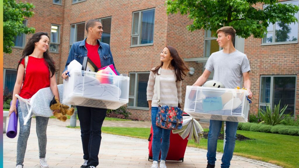 Students carrying belongings into a student housing community during move-in day.