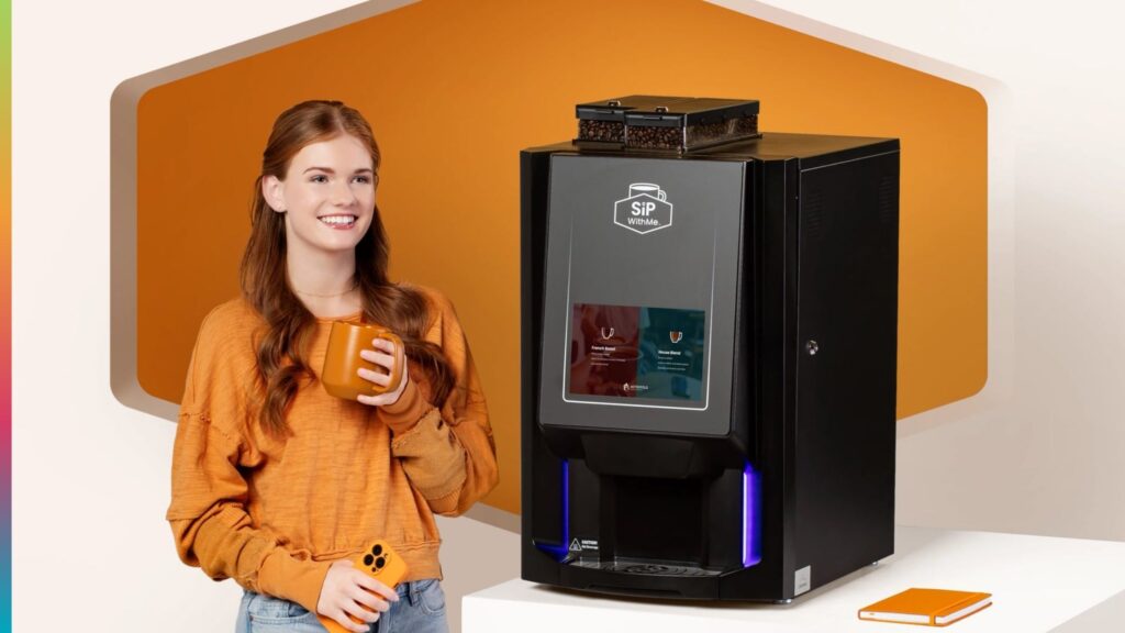 Hotel guest holding coffee beside a SipWithMe commercial coffee brewer.